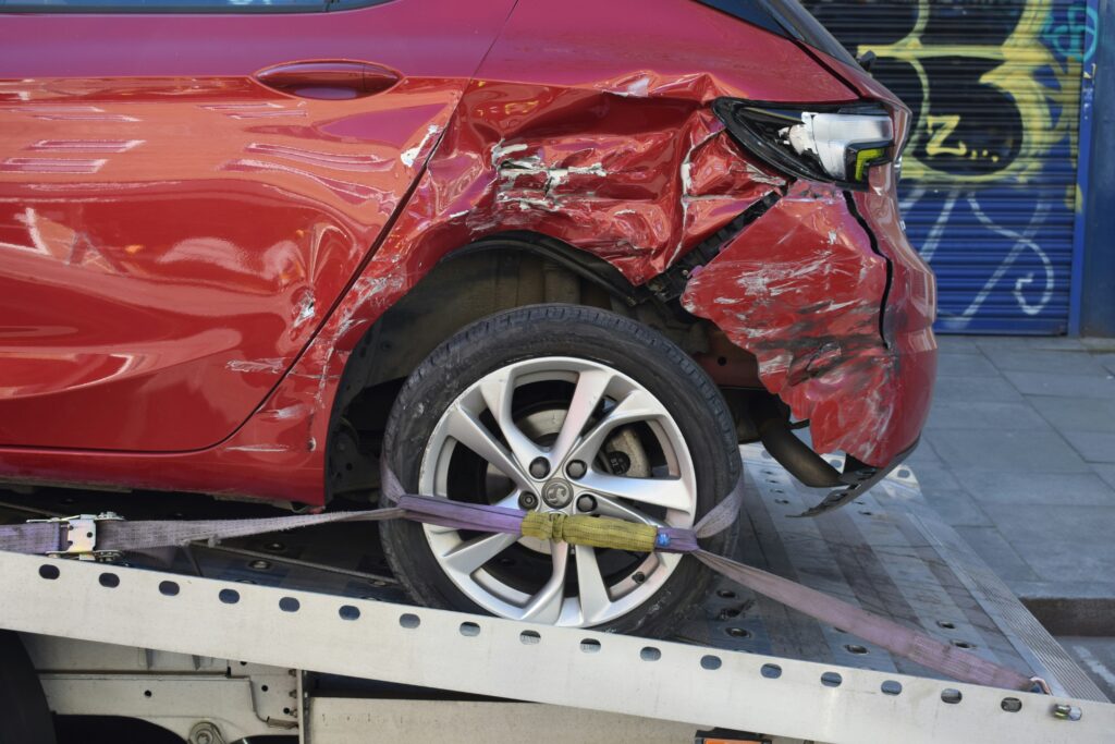 Towed red car with extensive damage, symbolizing the necessity for medical evaluation after an auto accident.
