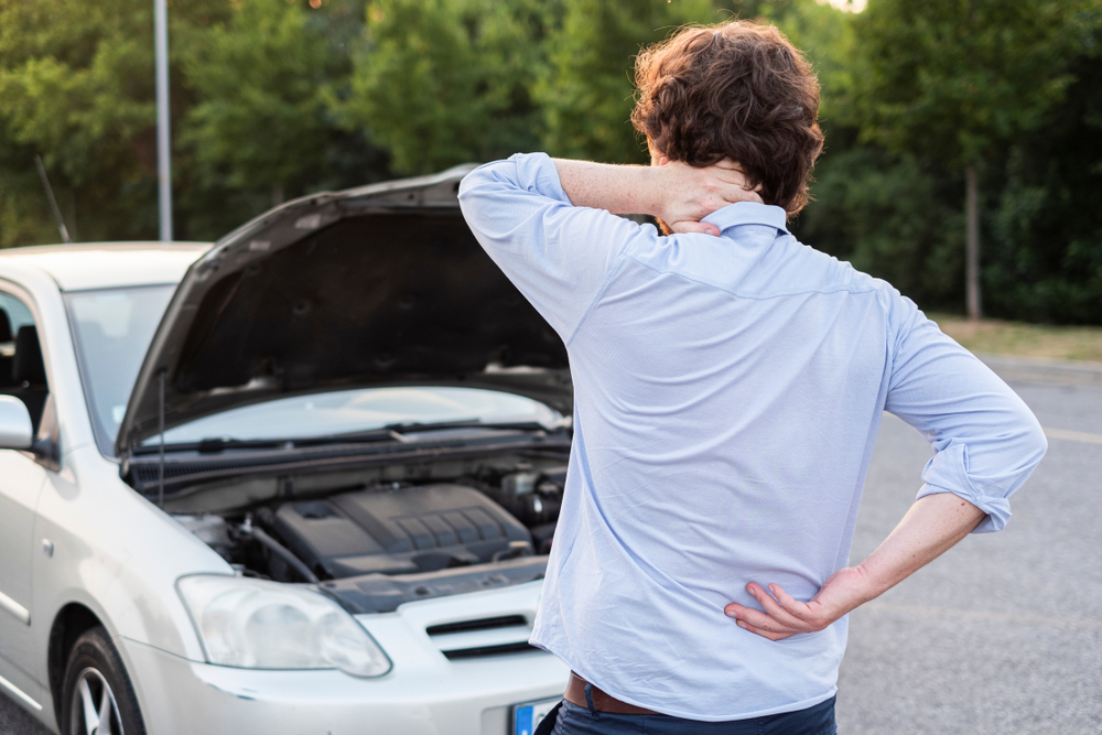 Individual assessing pain in neck and back following a vehicle collision.
