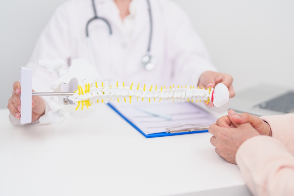 A spine specialist inspects a model of the spine, highlighting concerns related to fall injuries.