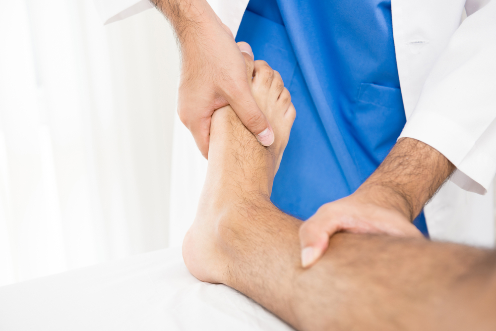A doctor inspects a patient's foot, evaluating for potential injuries after a slip and fall accident.